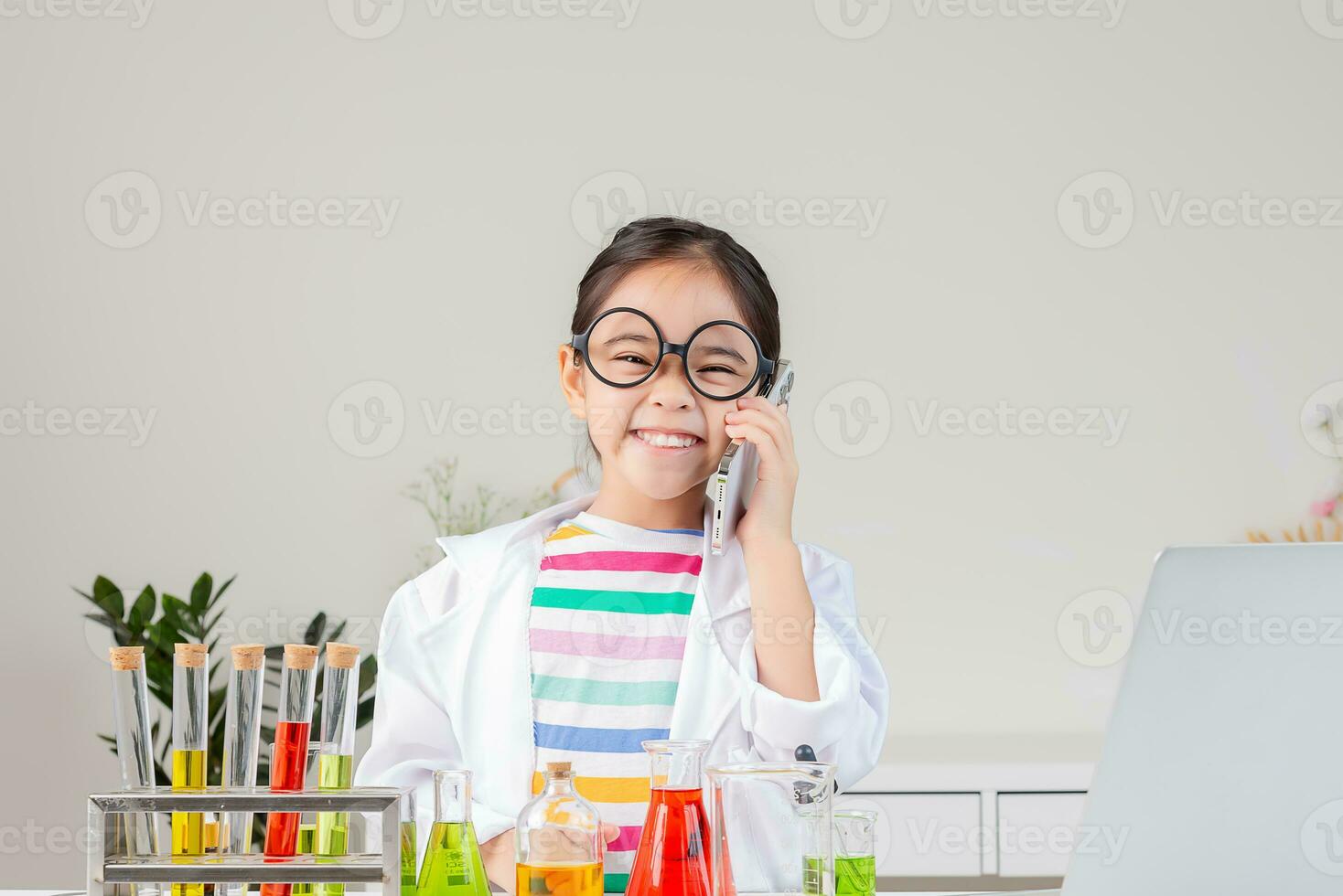 Asian little girl working with test tube science experiment in white classroom photo