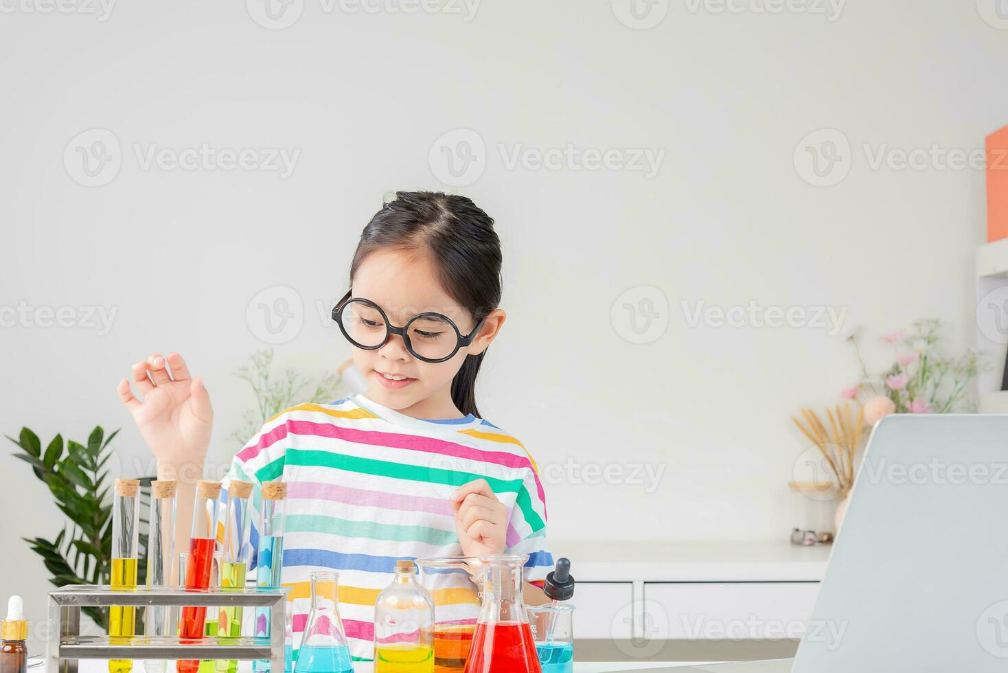 Asian little girl working with test tube science experiment in white classroom photo