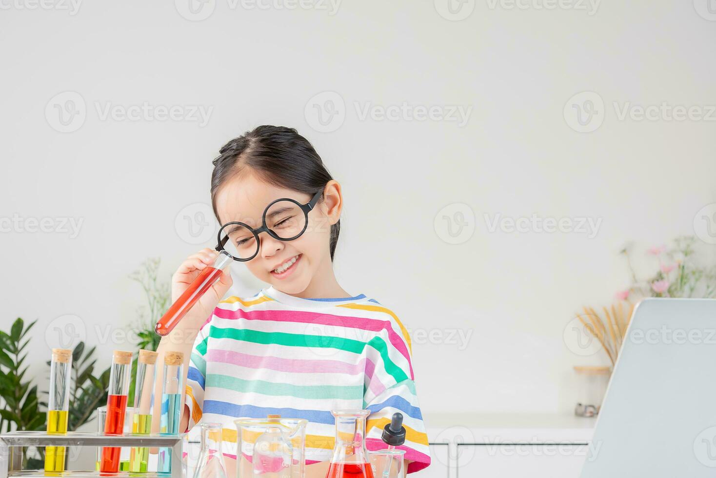 Asian little girl working with test tube science experiment in white classroom photo