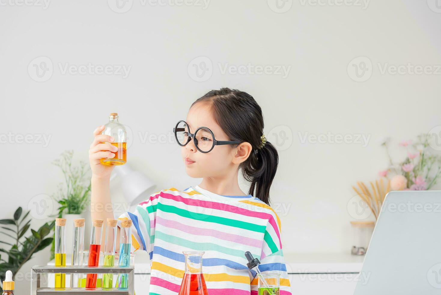 Asian little girl working with test tube science experiment in white classroom photo