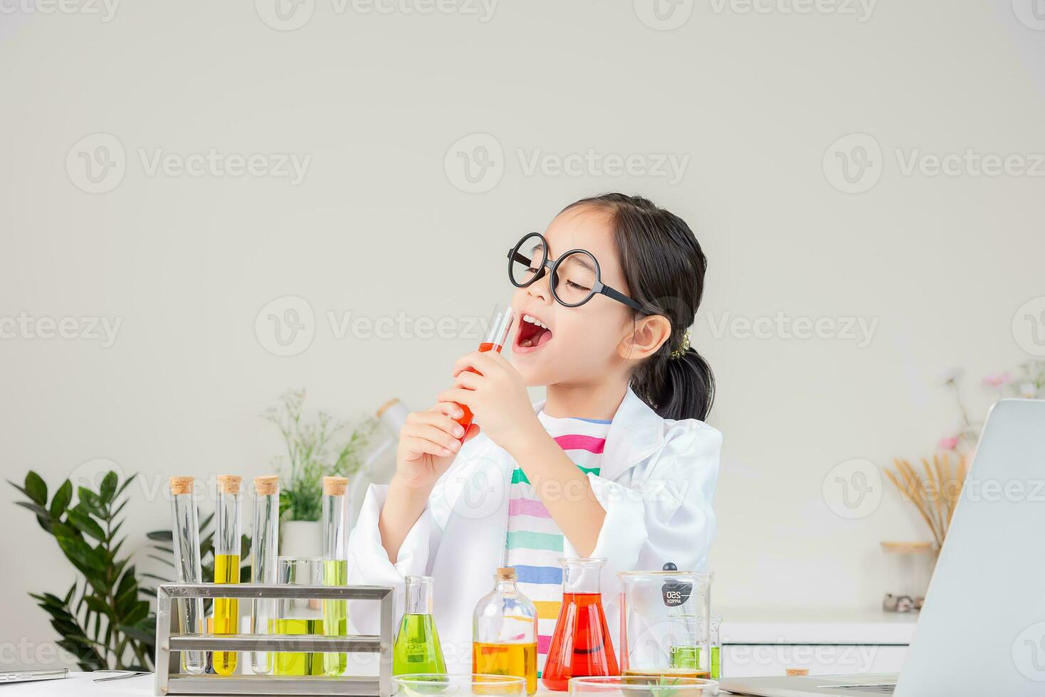 Asian little girl working with test tube science experiment in white classroom photo