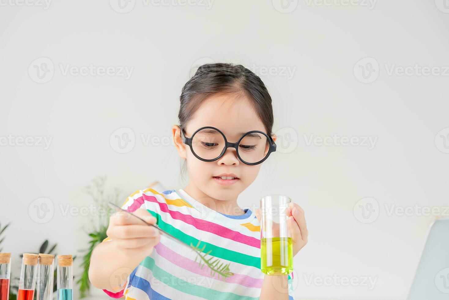 Asian little girl working with test tube science experiment in white classroom photo