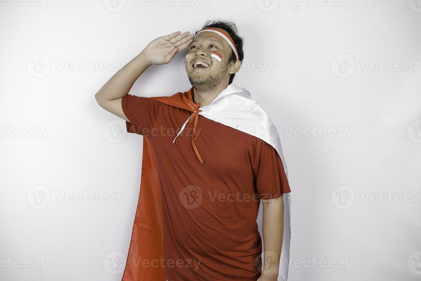 Indonesian man give salute with proud gesture while holding Indonesia's flag. Indonesia's independence day concept. photo