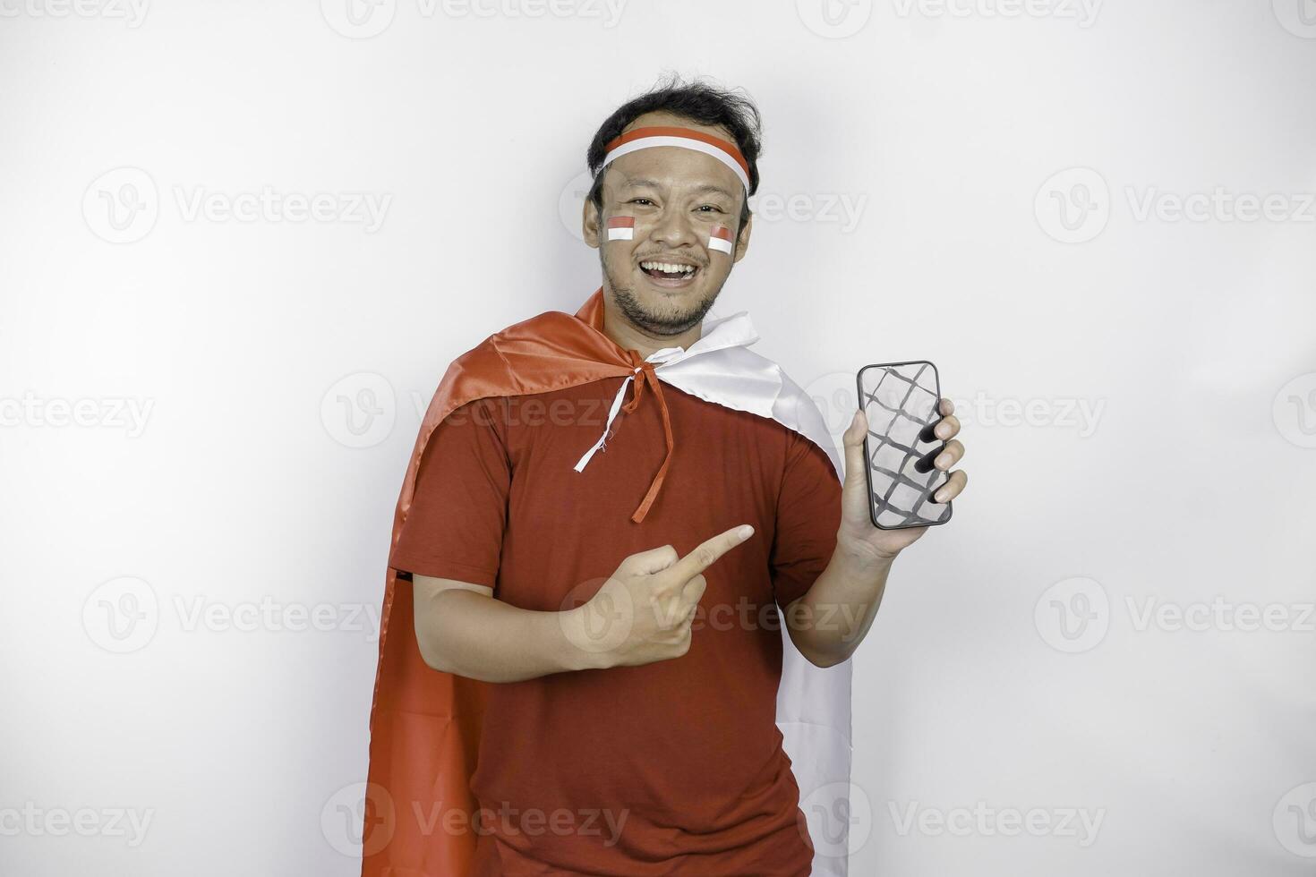 A portrait of a smiling Asian man wearing headband and showing his phone, isolated by white background. Indonesia's independence day concept photo