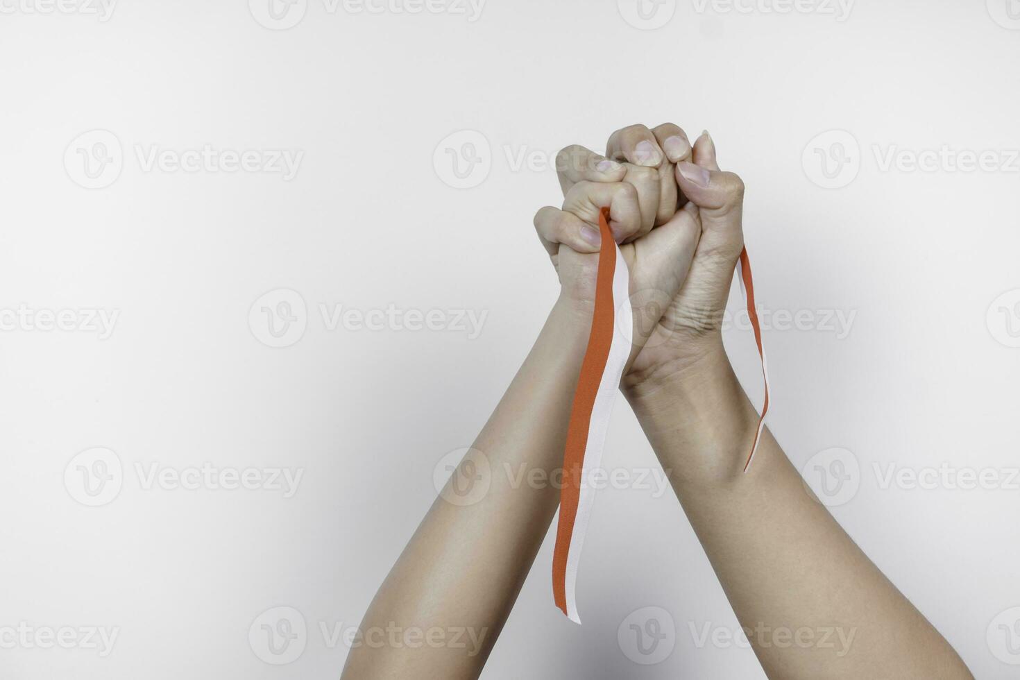 hands put together holding Indonesian red and white ribbon. Indonesia's independence day concept photo