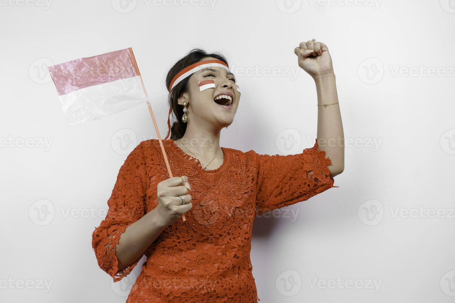 A young Asian woman with a happy successful expression wearing red kebaya and headband isolated by white background. Indonesia's independence day concept. photo