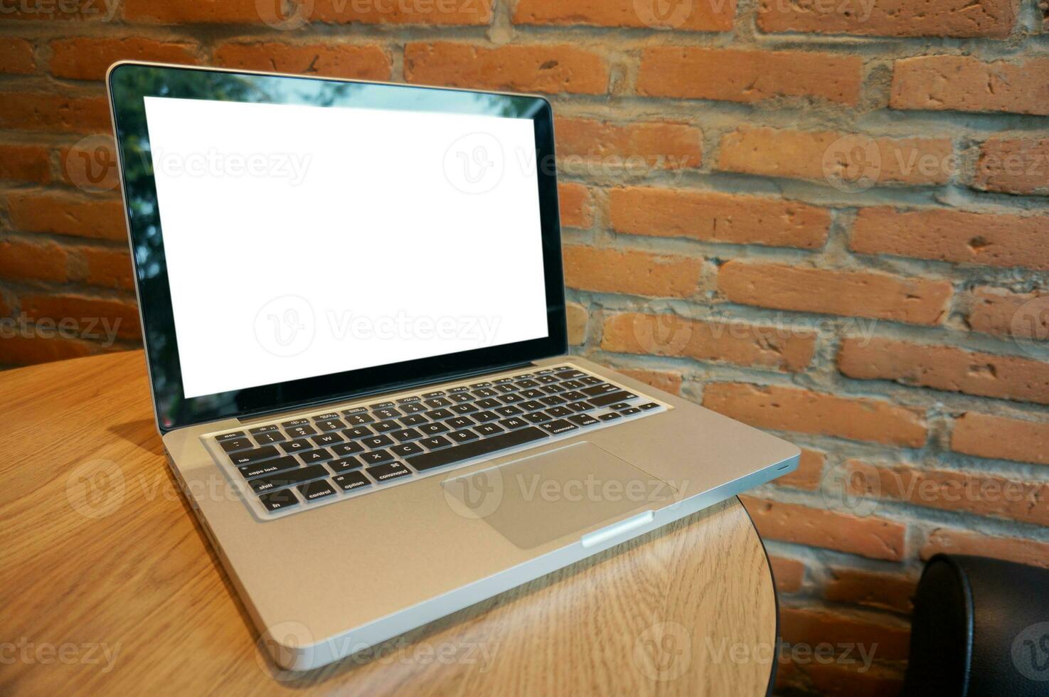 ordenador portátil con burlarse de arriba blanco pantalla en de madera mesa en frente de café espacio para texto. producto monitor computadora ordenador portátil montaje- tecnología Lanza libre trabajo concepto foto