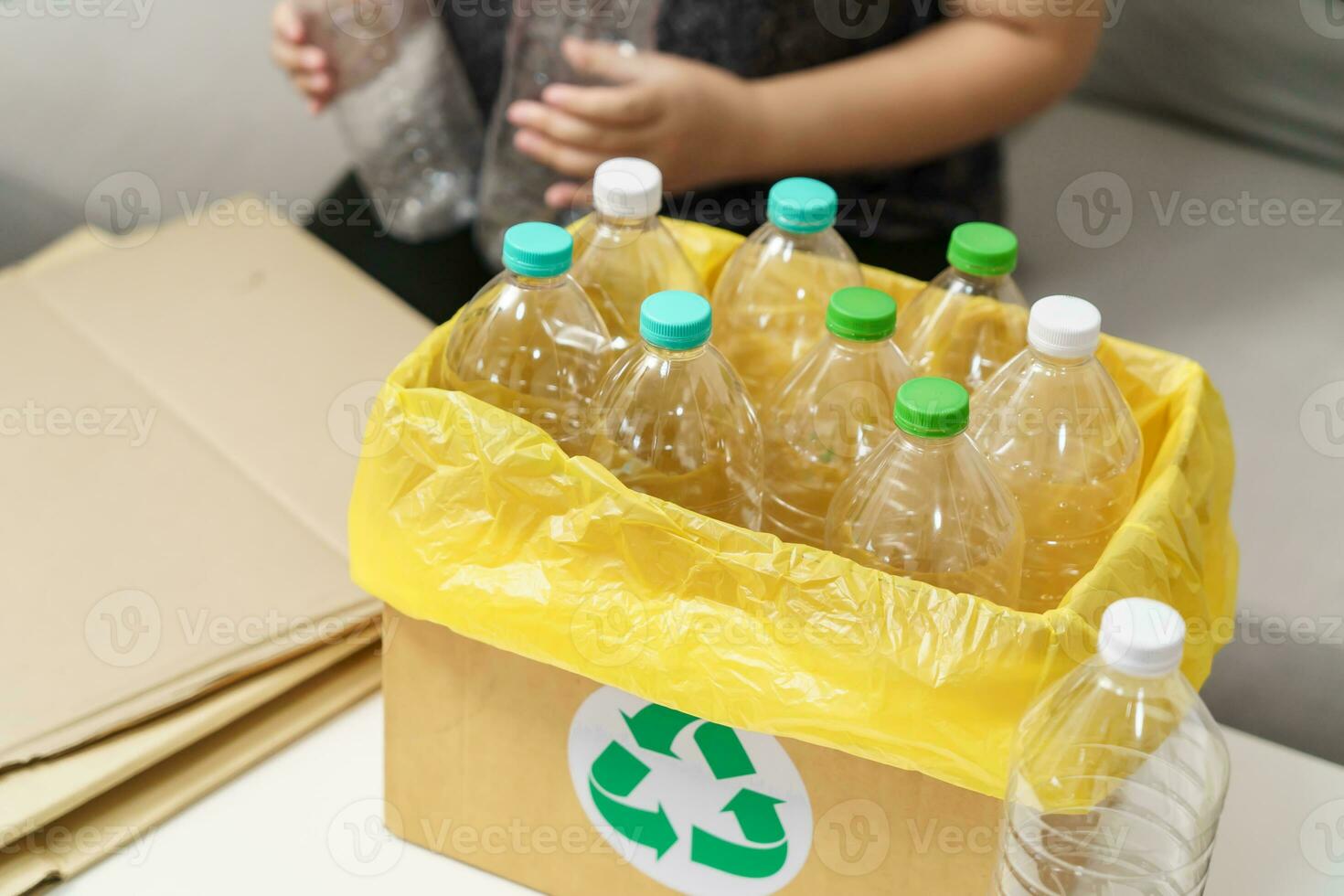 Home recycle eco green zero concept Woman throwing empty plastic bottle in recycling bin with yellow garbage bags at home. photo