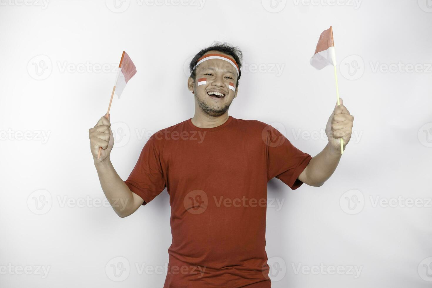 Happy smiling Indonesian man holding Indonesia's flag to celebrate Indonesia Independence Day isolated over white background. photo