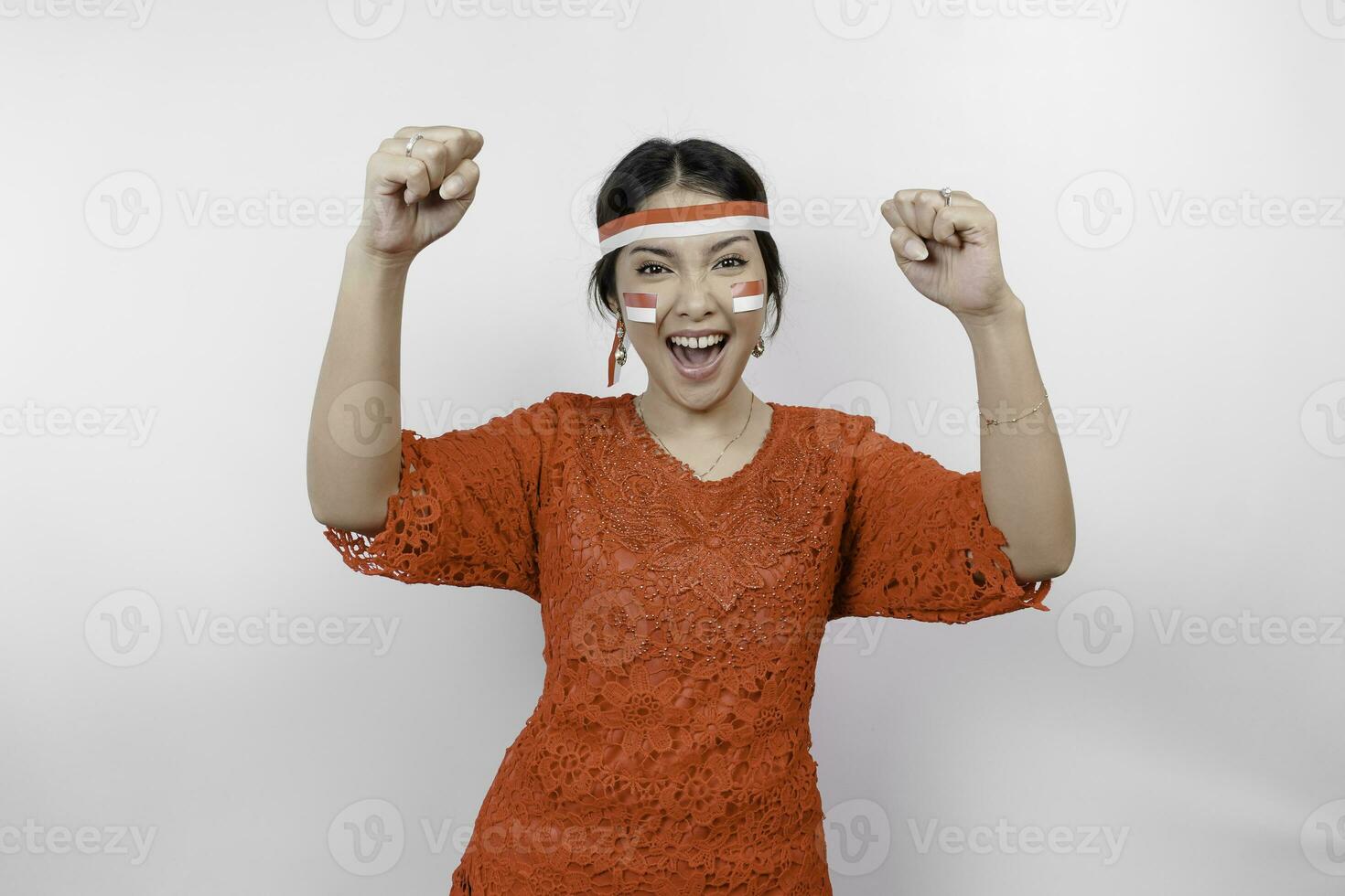 A young Asian woman with a happy successful expression wearing red kebaya and headband isolated by white background. Indonesia's independence day concept. photo