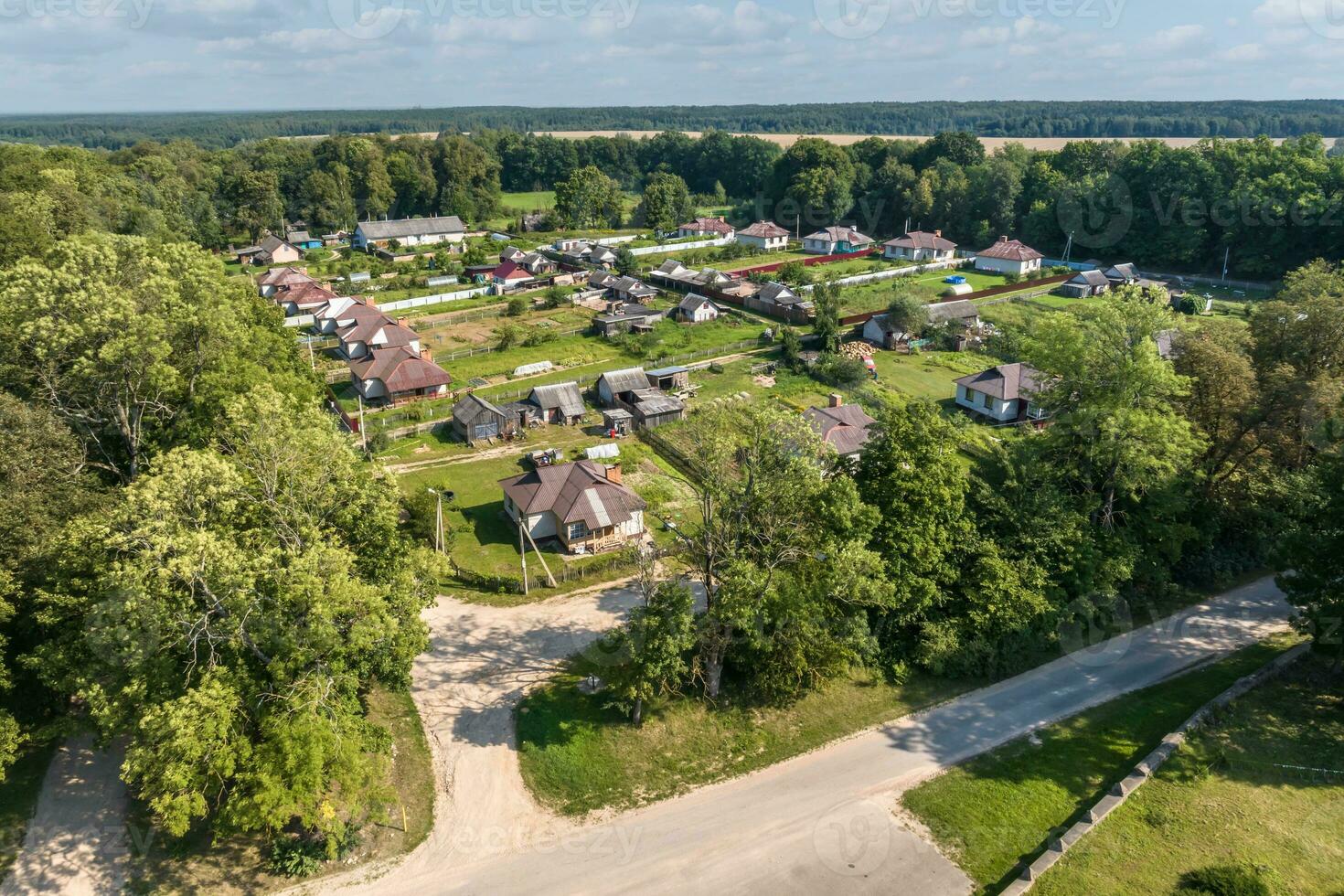 panoramic aerial view of eco village with wooden houses, gravel road, gardens and orchards photo