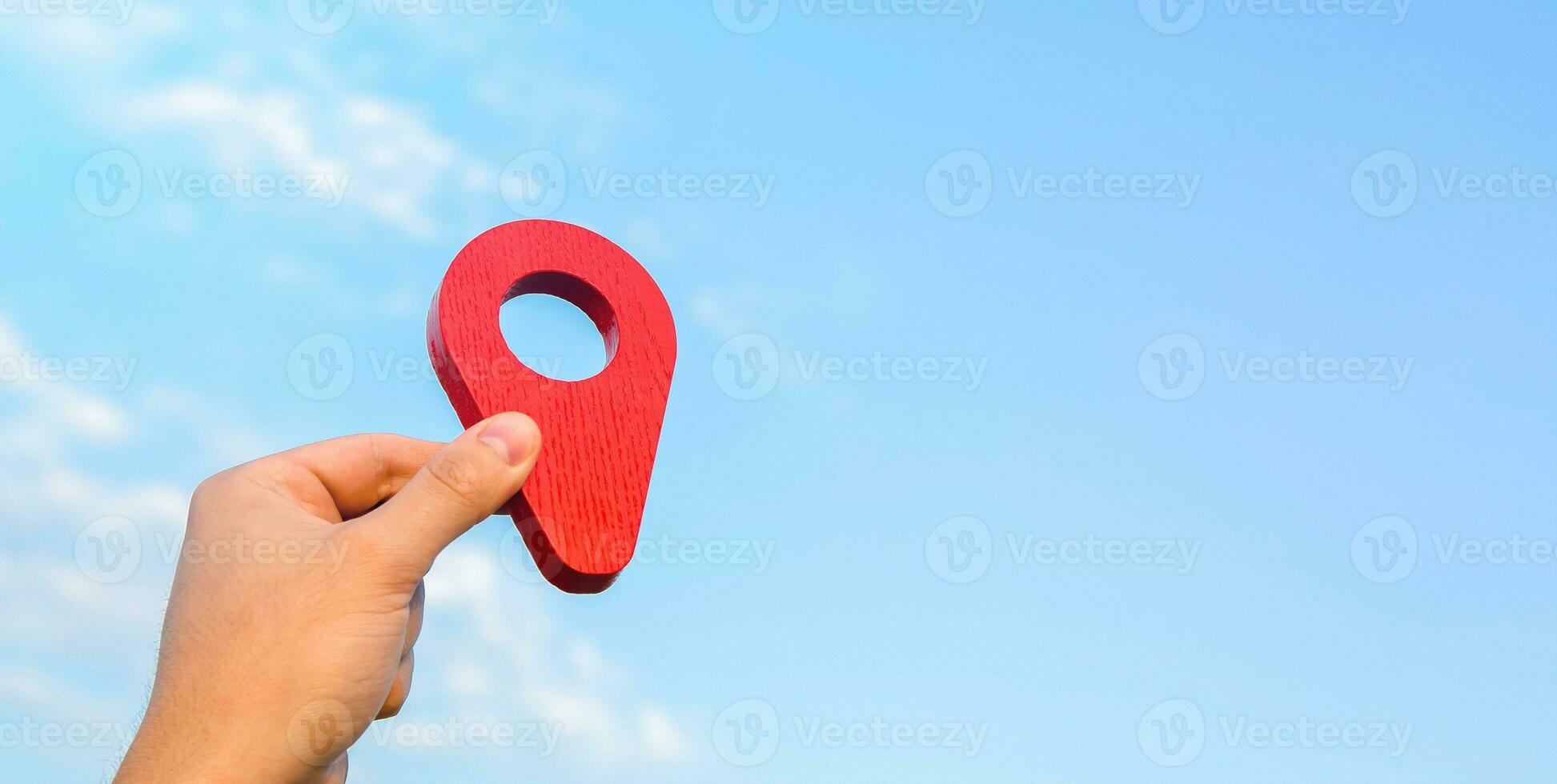 Holding a red location pin pointer in the sky. Tourism and travel. The concept of freedom and open borders, exploration and adventure. Going on vacation. A dream come true. Navigation guide photo