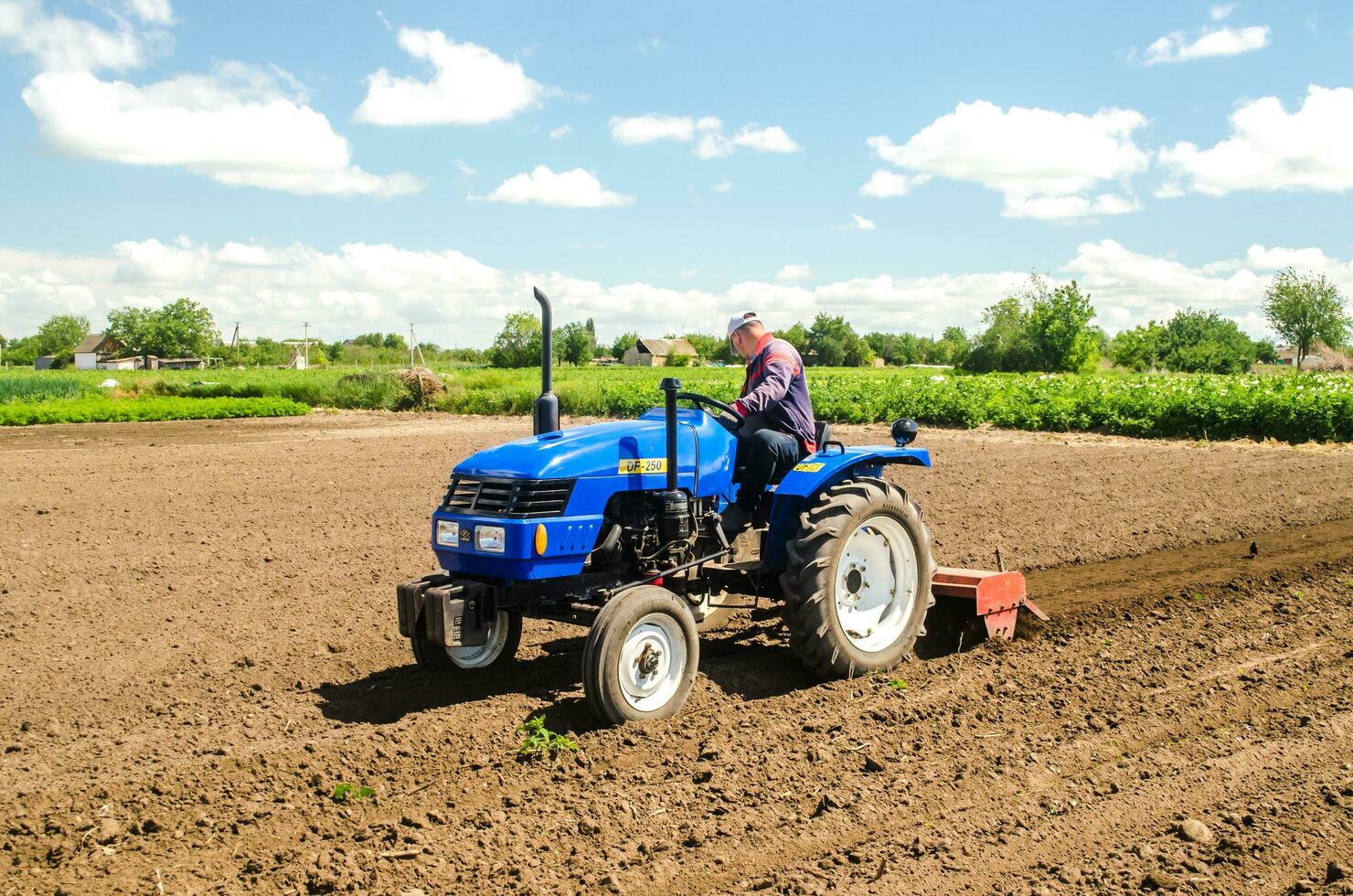 Kherson oblast, Ukraine May 28, 2020 Farmer cleans and turns the soil in the farm field for further sowing with agricultural crops. Loosening surface, land cultivation. Farming, agriculture. photo