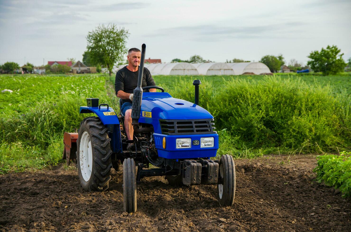 Kherson oblast, Ukraine - May 29, 2021 Farmer on a tractor works in the field. Seasonal worker. Recruiting workers with skills in driving agricultural machinery. Milling soil before cutting rows. photo