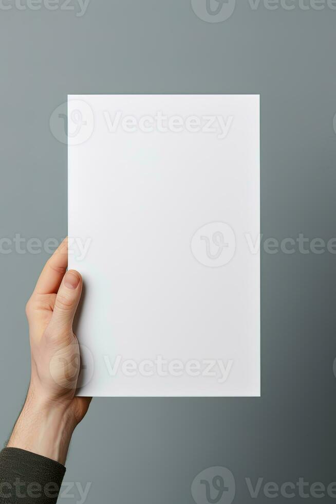 A human hand holding a blank sheet of white paper or card isolated on grey background. ai generated photo