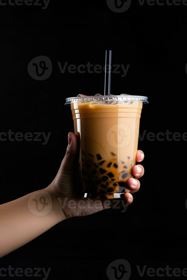 A hand holding takeaway plastic cup of delicious iced bubble milk tea and black pearls isolated on black background. ai generated photo