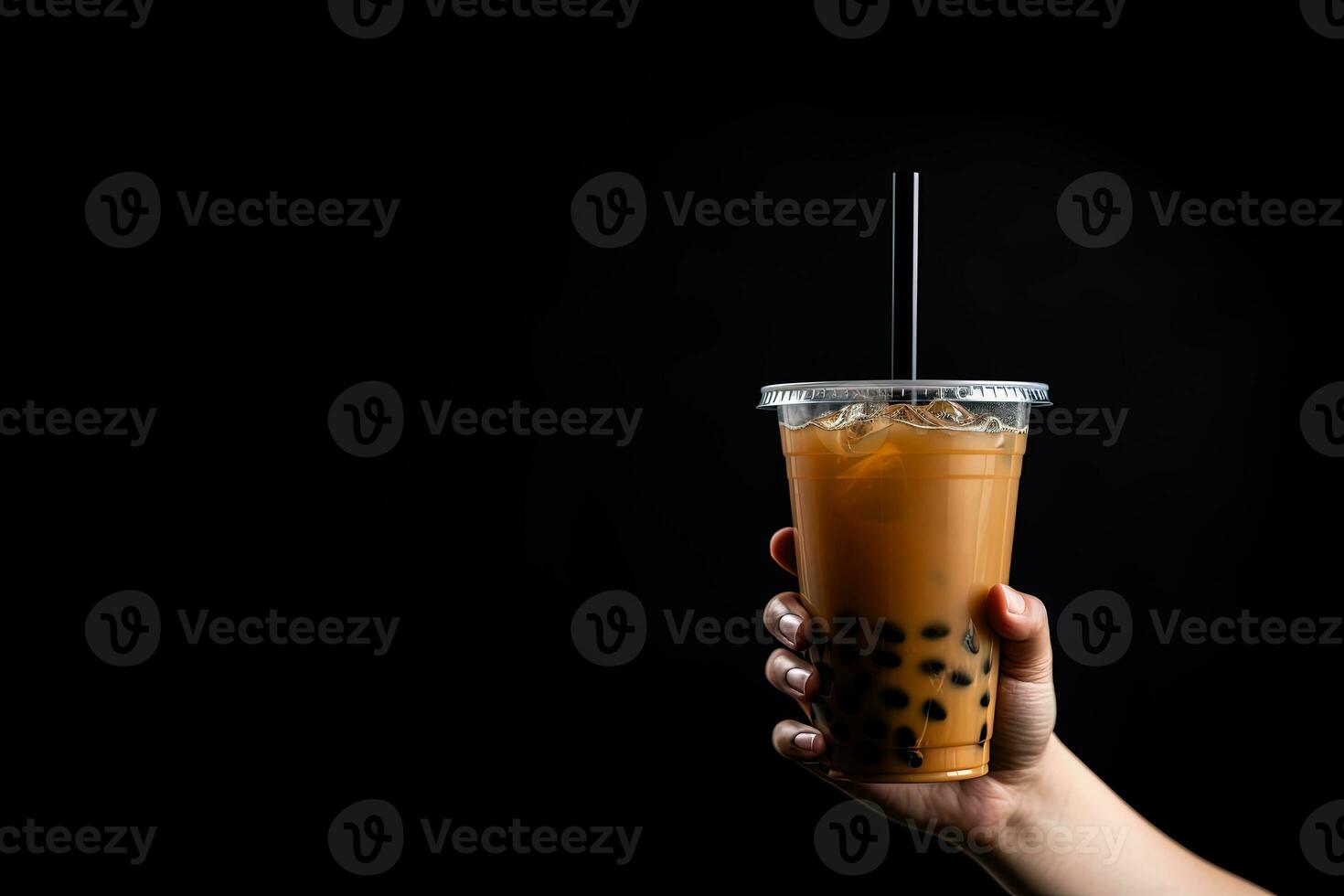 A hand holding takeaway plastic cup of delicious iced bubble milk tea and black pearls isolated on black background with copy space. ai generated photo