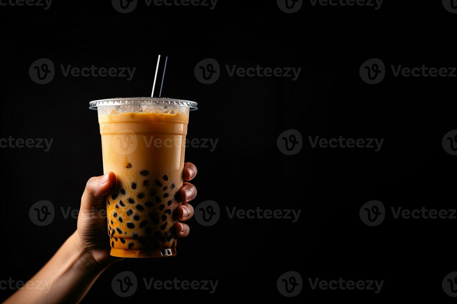 A hand holding takeaway plastic cup of delicious iced bubble milk tea and black pearls isolated on black background with copy space. ai generated photo