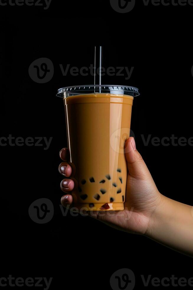 A hand holding takeaway plastic cup of delicious iced bubble milk tea and black pearls isolated on black background. ai generated photo