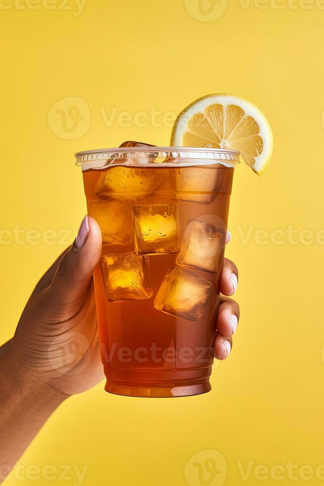 A hand holding takeaway plastic cup of delicious iced lemon tea isolated on yellow background. ai generated photo