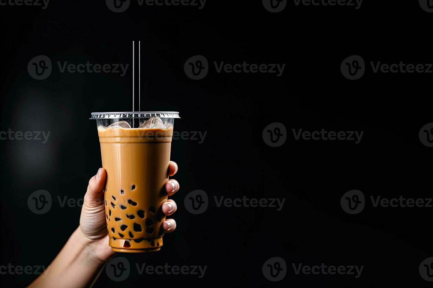 A hand holding takeaway plastic cup of delicious iced bubble milk tea and black pearls isolated on black background with copy space. ai generated photo