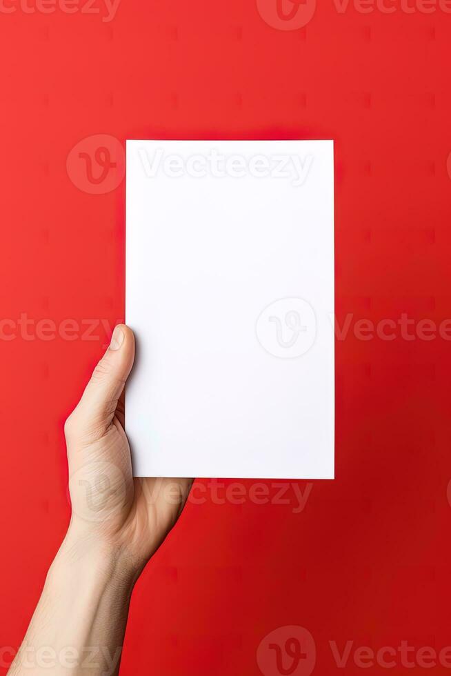 A human hand holding a blank sheet of white paper or card isolated on red background. ai generated photo