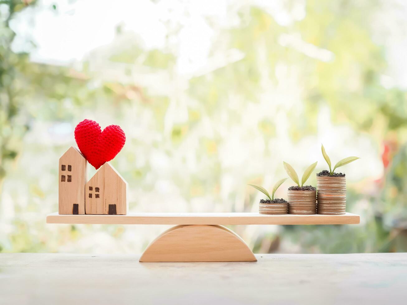 Plants growing up on stack of coins and miniature house on balancing scale for mortgage investment , property concept photo