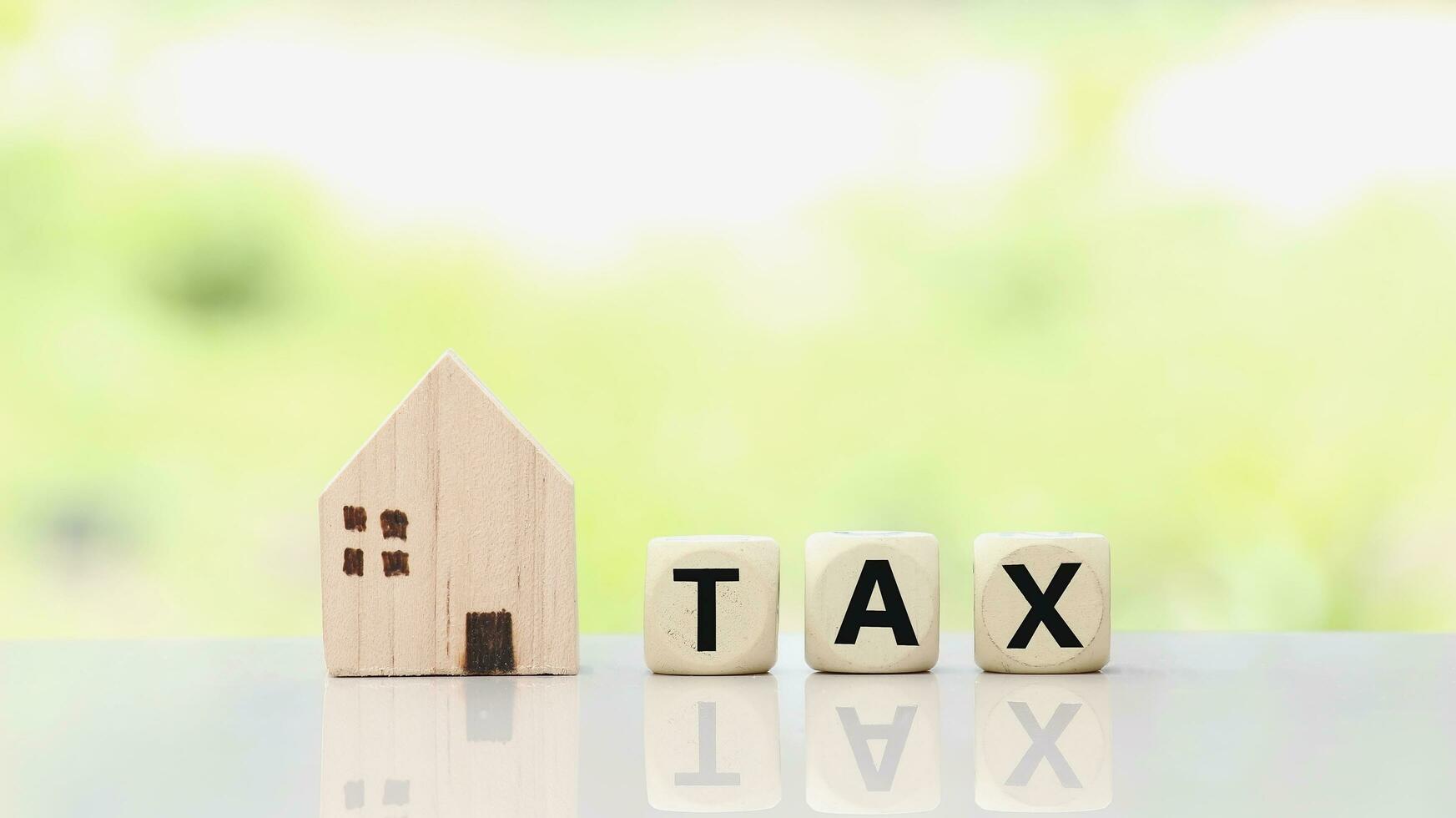 Miniature house and tax wooden cube for Investment property concepy photo
