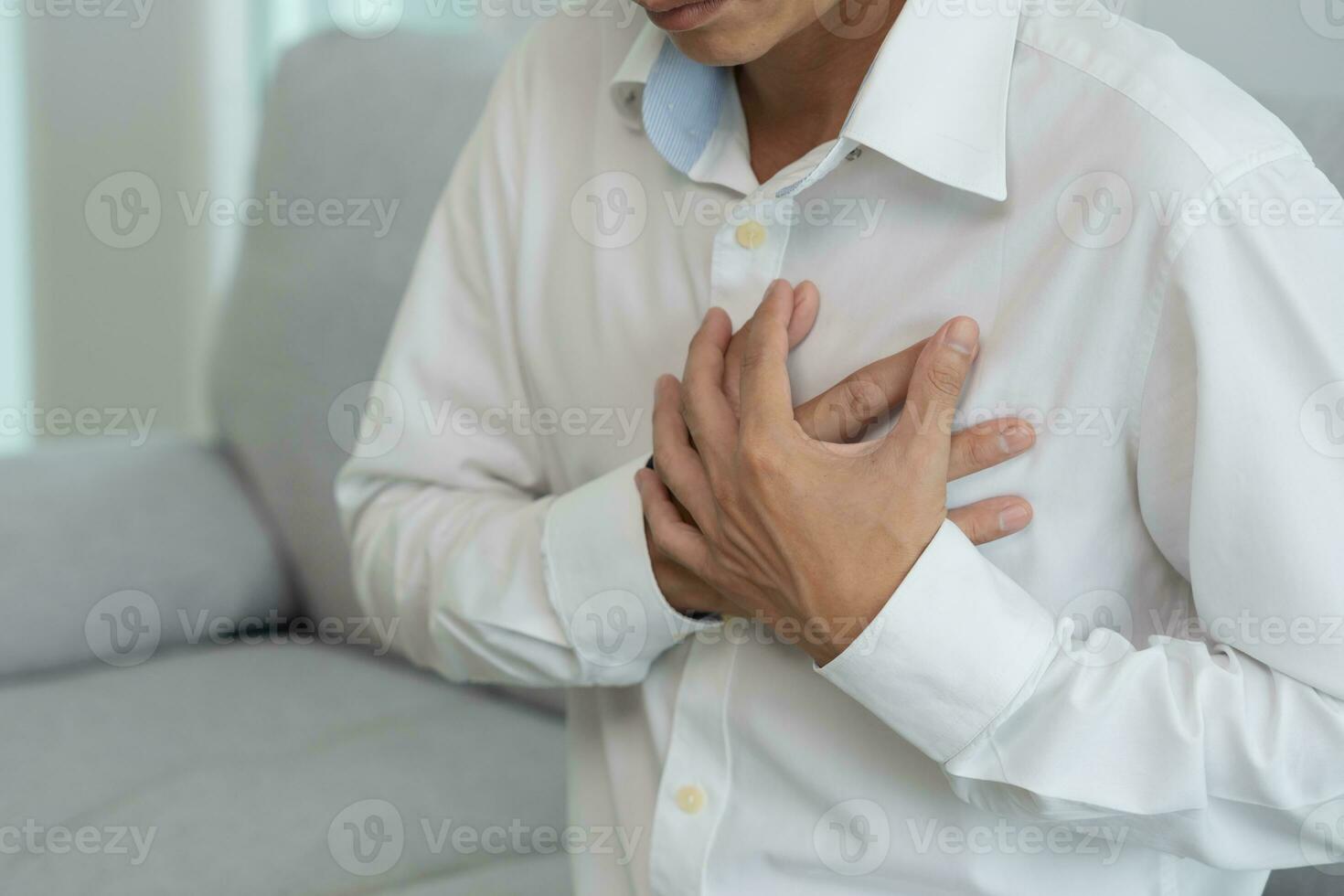 hand hold chest with heart attack symptoms, asian man working hard have chest pain caused by heart disease, leak, dilatation, enlarged coronary heart, press on the chest with a painful expression photo