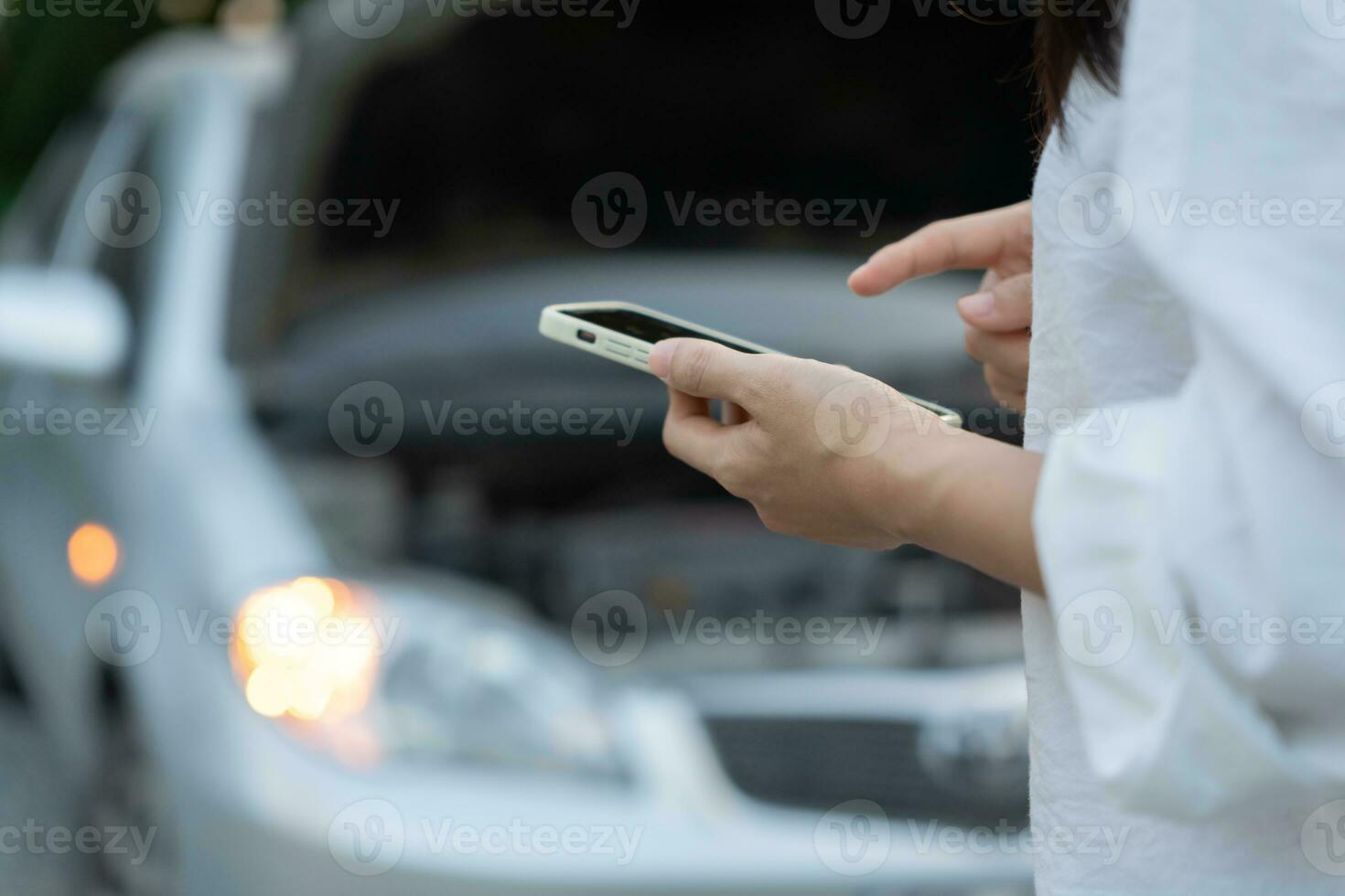 breakdown, broken car, repair. Woman uses mobile phone check insurance premiums through application due to car accident . Find garage to get car fixed during country tour, waiting for help, emergency. photo