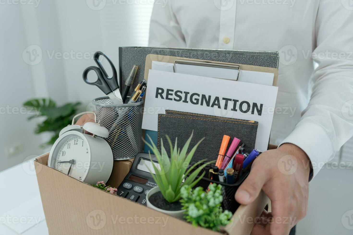 los empresarios estresantes renunciarán a la empresa. él está levantando una caja de papel marrón que contiene artículos personales. concepto de renuncia, colocación laboral y vacantes. foto