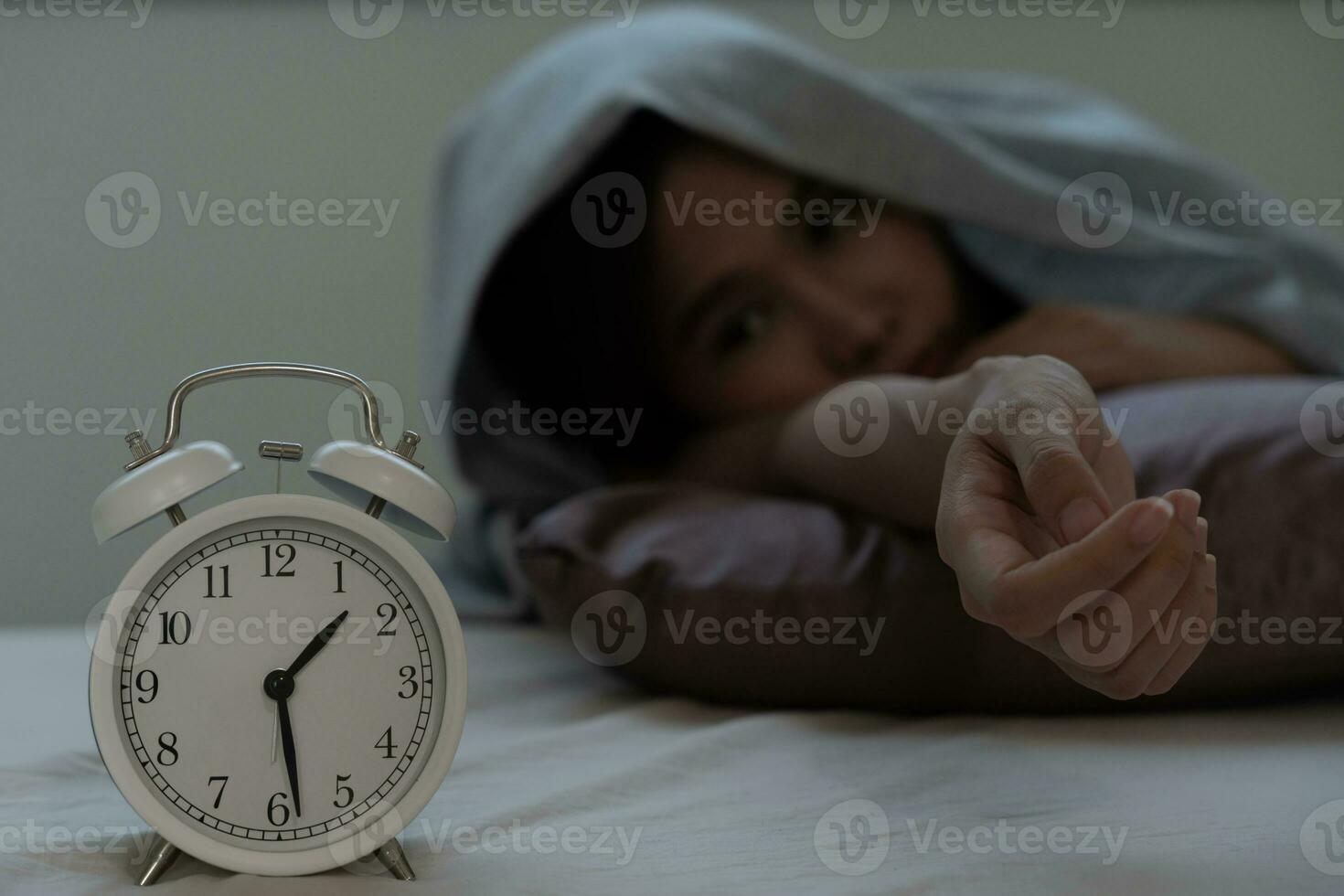 asian woman in bed late trying to sleep suffering insomnia, sleepless or scared in a nightmare, looking sad worried and stressed. Tired and headache or migraine waking up in the middle of the night. photo