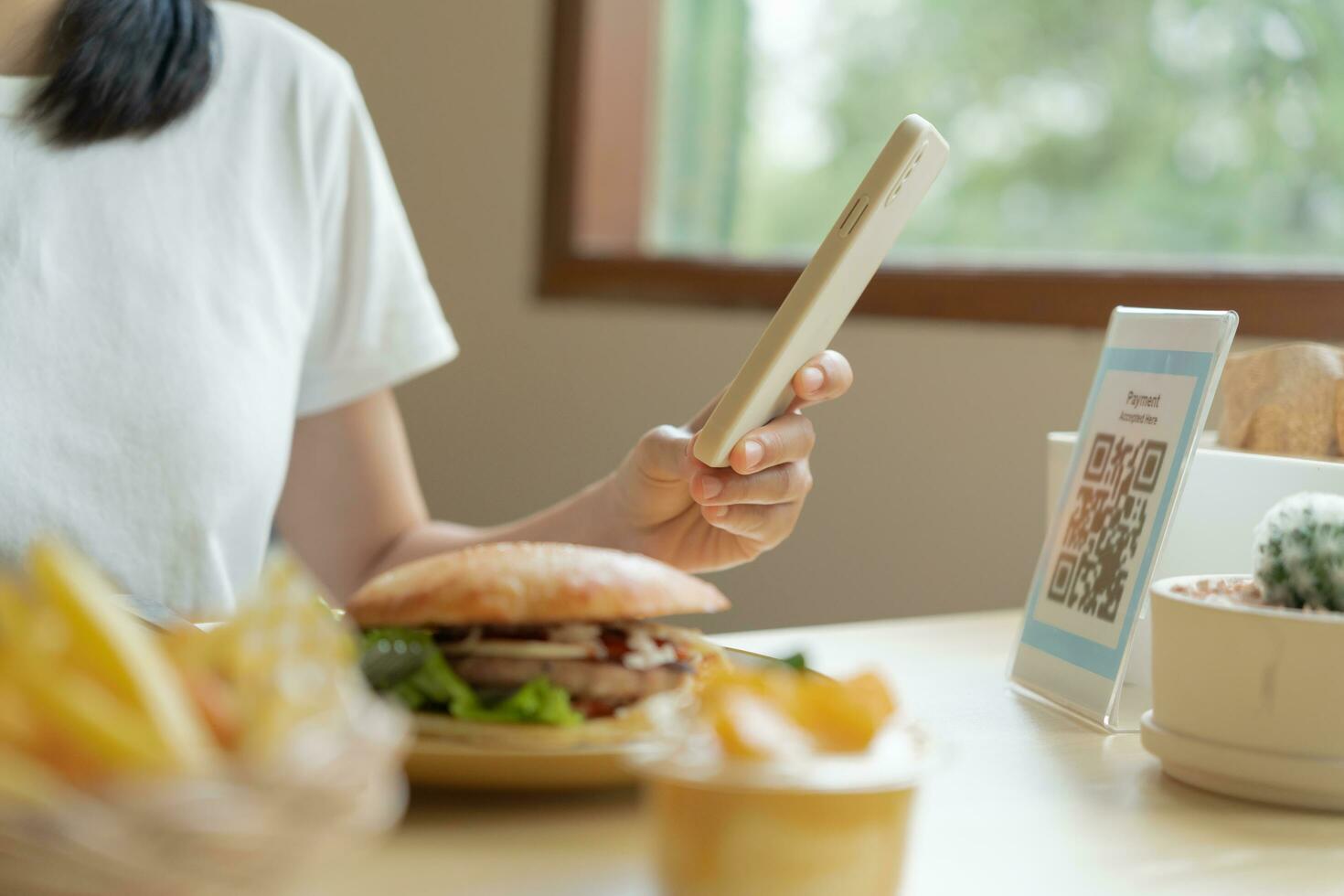 Woman use smartphone to scan QR code for order menu in cafe restaurant with a digital delivery. Choose menu and order accumulate discount. E wallet, technology, pay online, credit card, bank app. photo