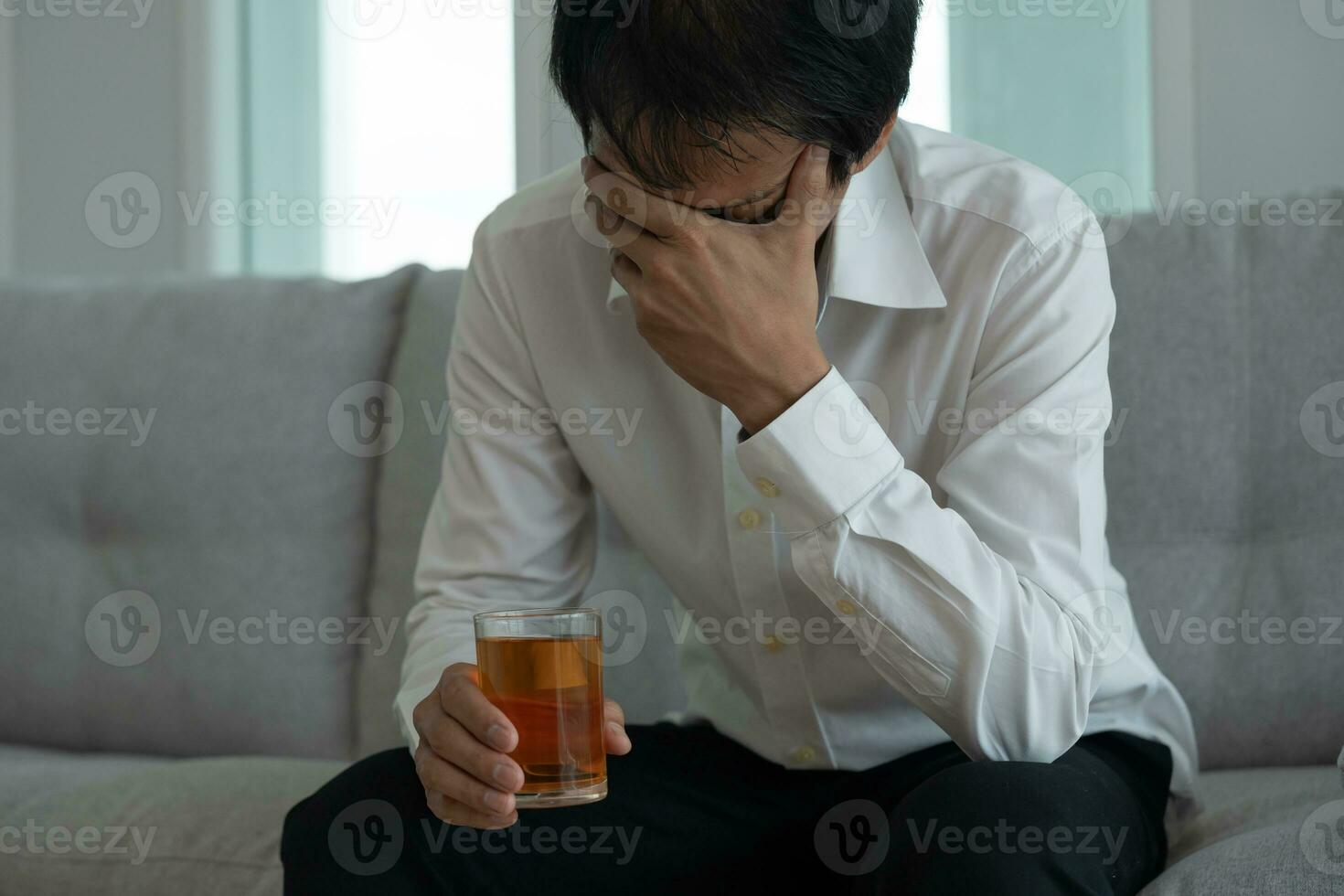 Depressed young business man addicted feeling bad drinking whiskey alone at home, stressed frustrated lonely drinking alcohol suffers from problematic liquor, alcoholism, life and family problems photo
