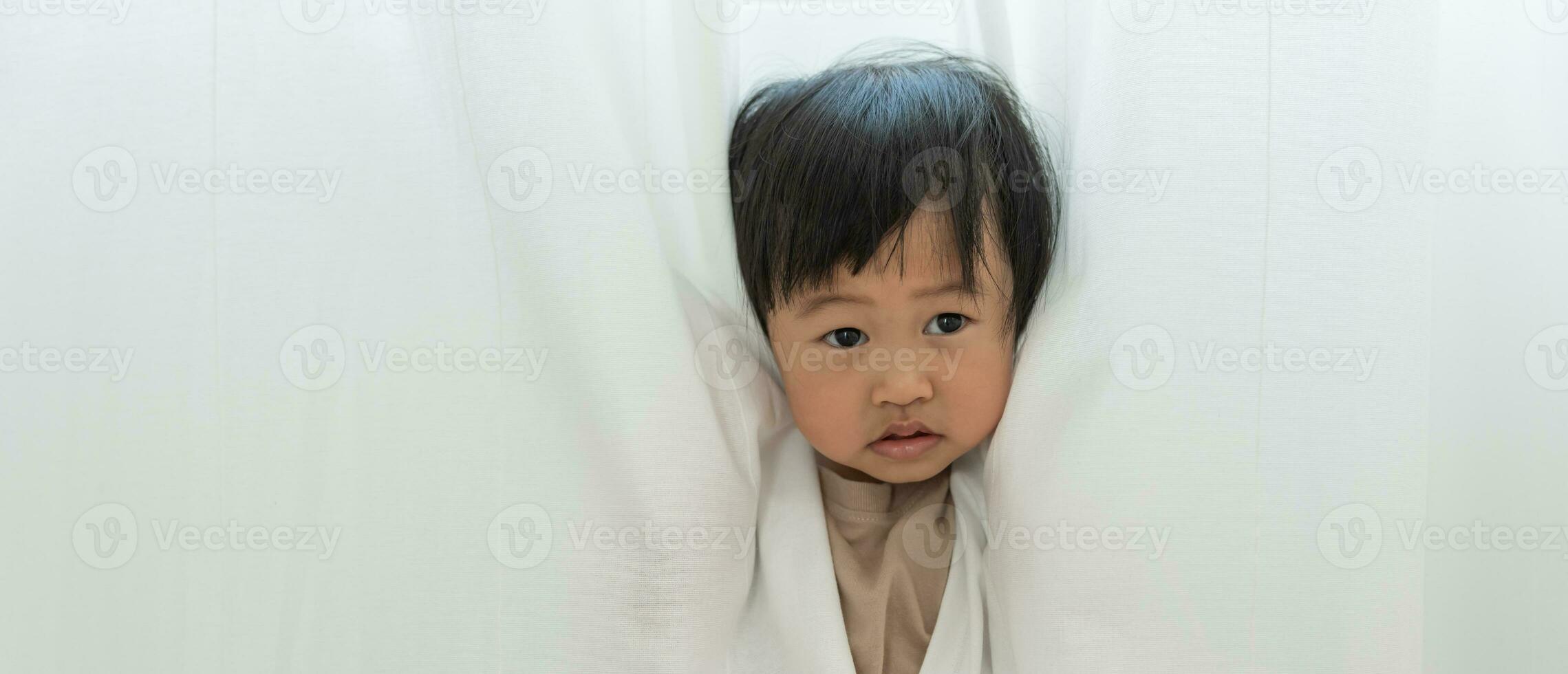 little asian children kid , playing hide and seek standing next a wall house, Adorable child having fun in the home. happy family have fun with kids, activity, learning photo