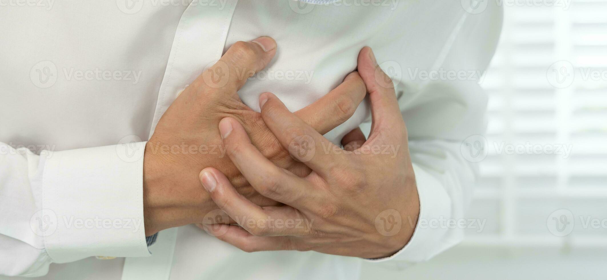 hand hold chest with heart attack symptoms, asian man working hard have chest pain caused by heart disease, leak, dilatation, enlarged coronary heart, press on the chest with a painful expression photo