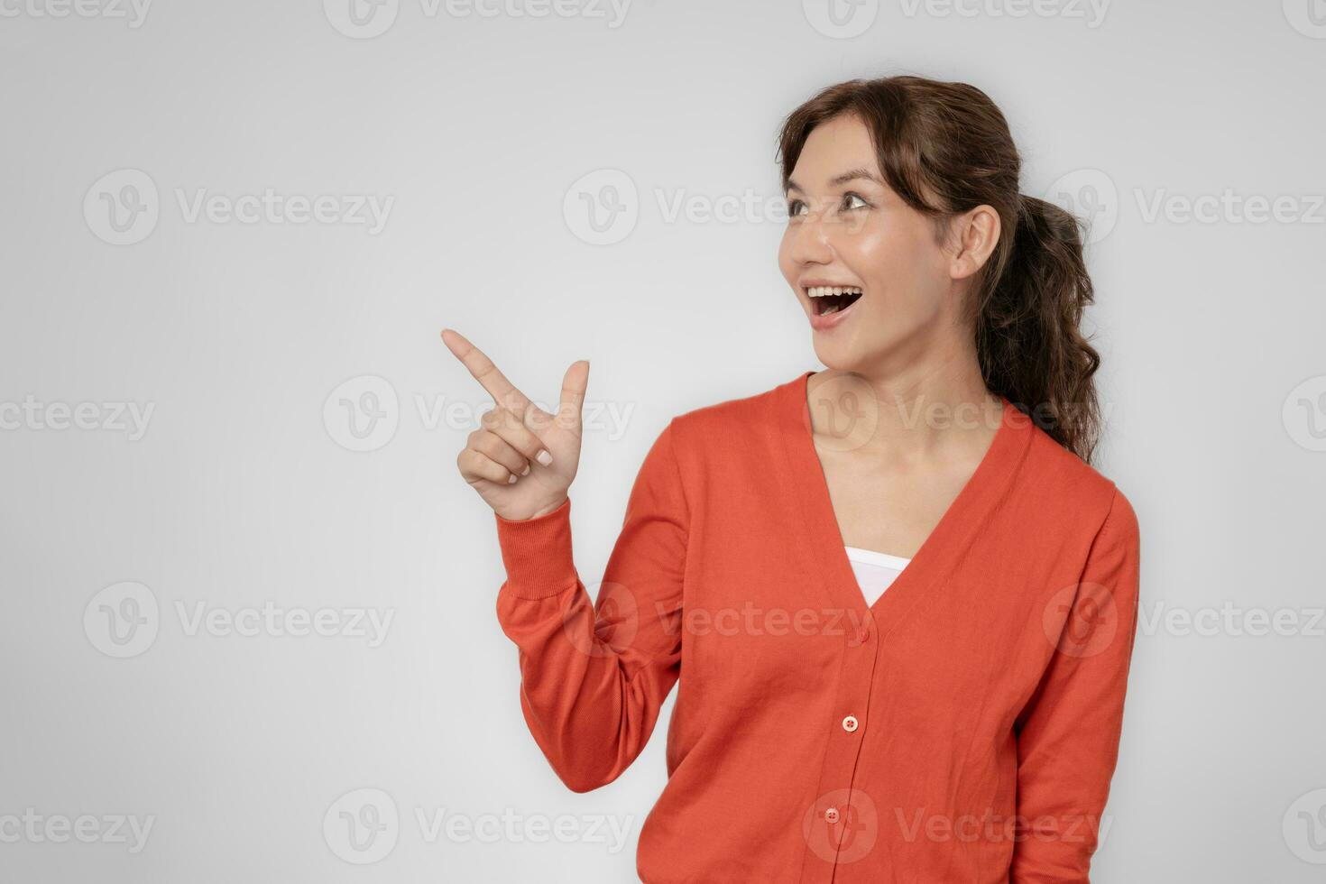 Portrait asian beautiful girl pointing blank space isolated background. Happy woman pointing on something. young female standing pointing finger sideways, billboard, introduction, advertisement, space photo