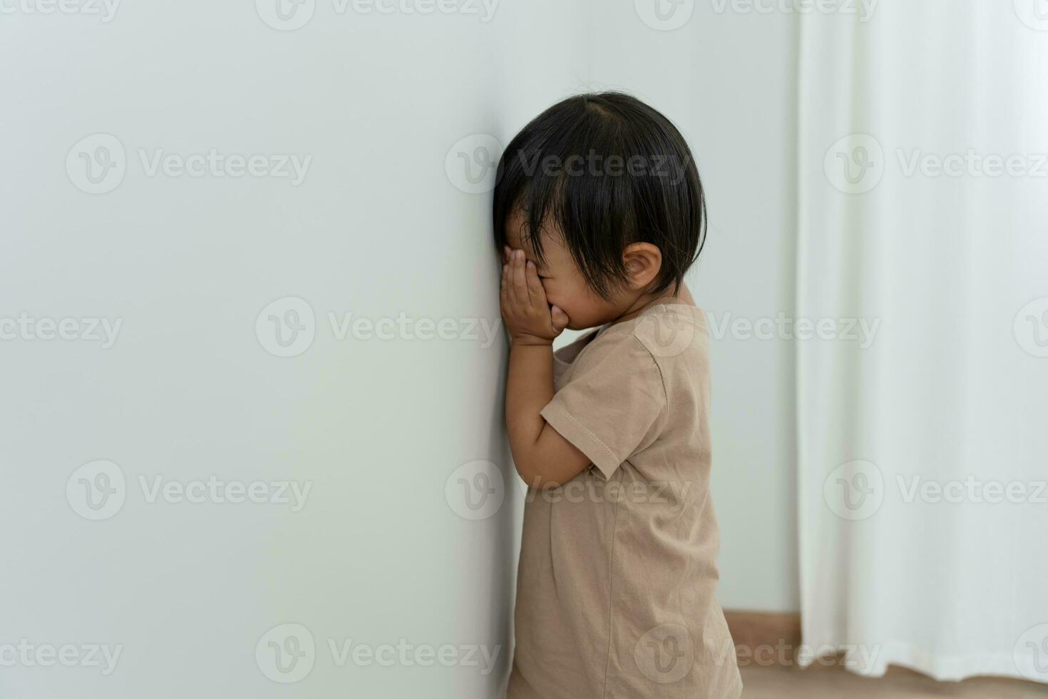 little asian children kid girl covering his eyes with hands, playing hide and seek standing next a wall house, Adorable child having fun in the home. happy family have fun with kids, activity photo