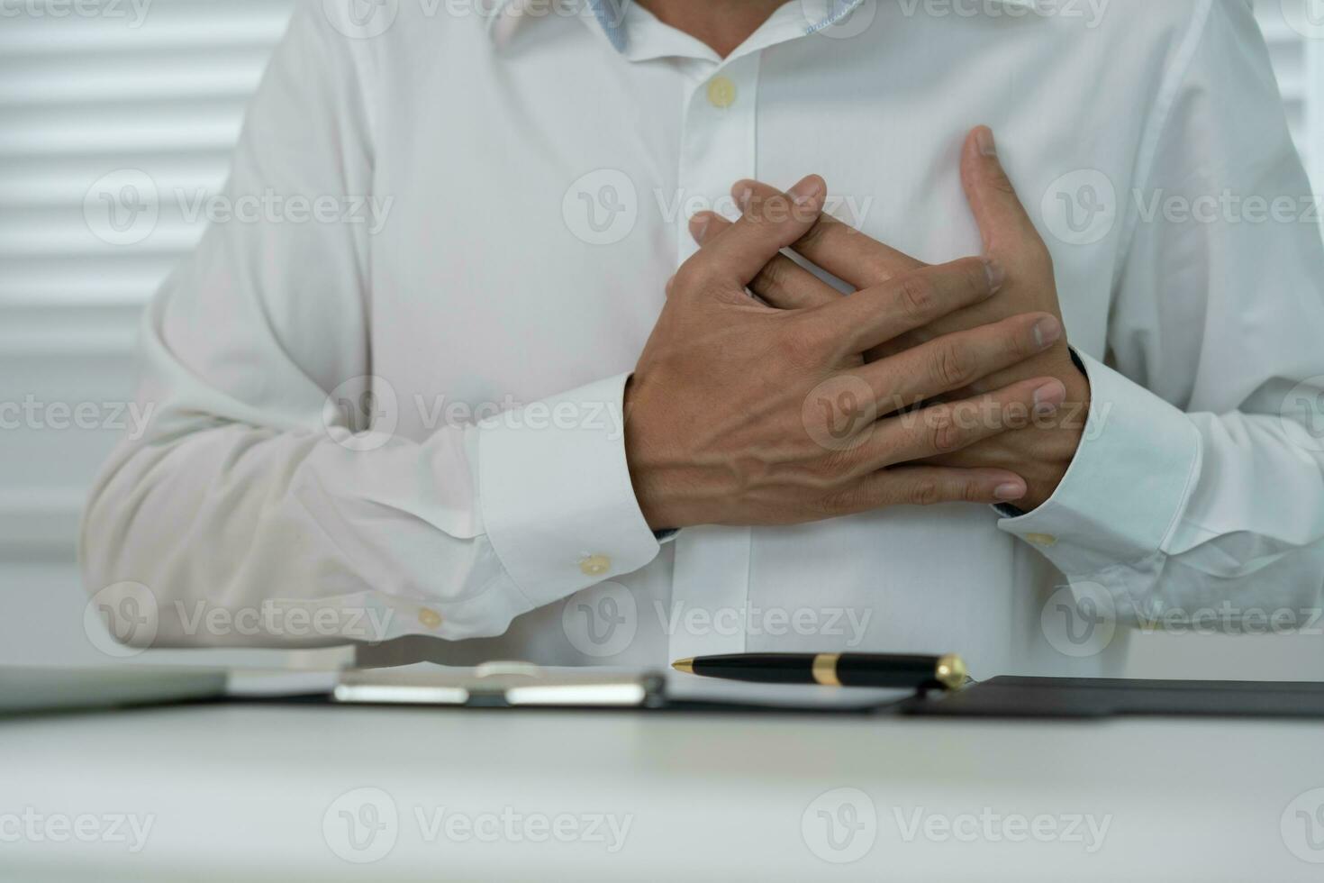 hand hold chest with heart attack symptoms, asian man working hard have chest pain caused by heart disease, leak, dilatation, enlarged coronary heart, press on the chest with a painful expression photo