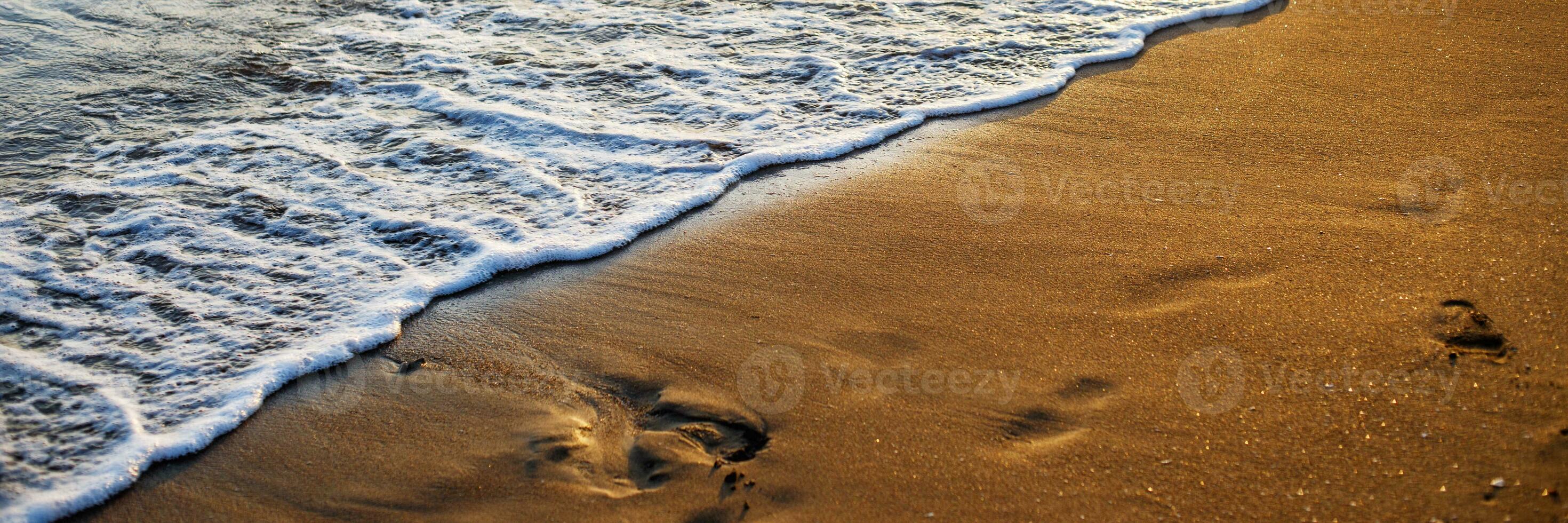 soft sea waves with a foam breaking on a sandy shore tropical beach at summer at sunset photo