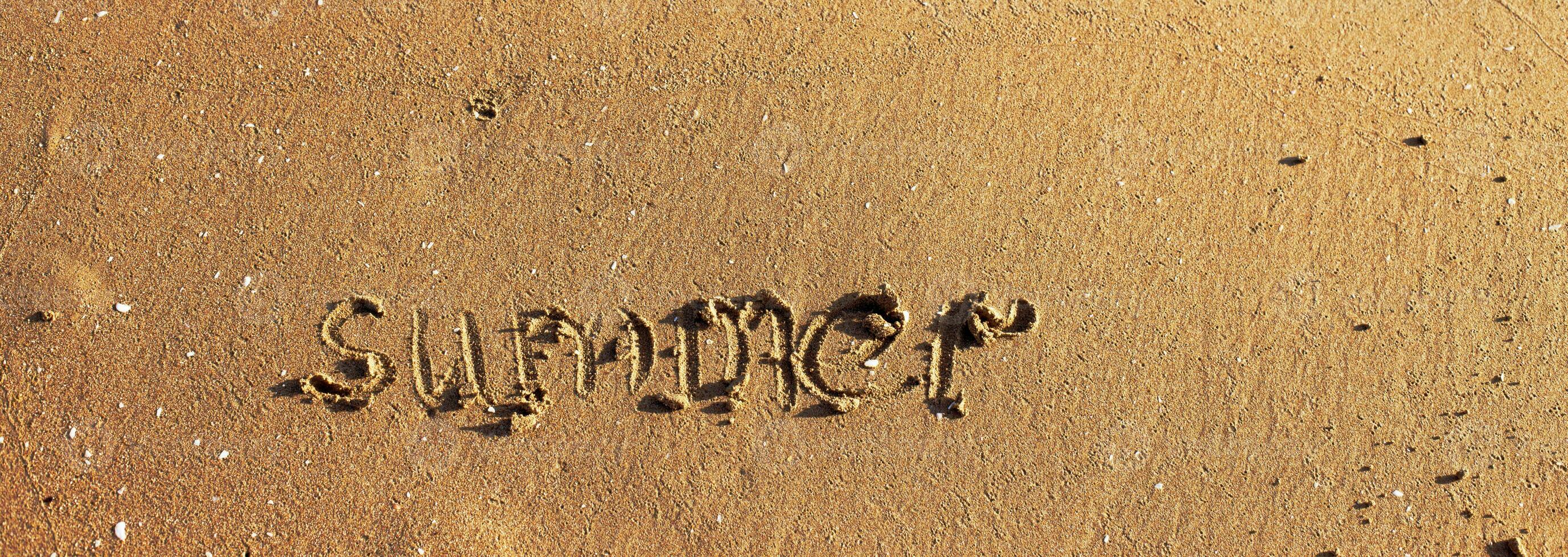 Word summer handwritten on the sandy beach and copy space photo