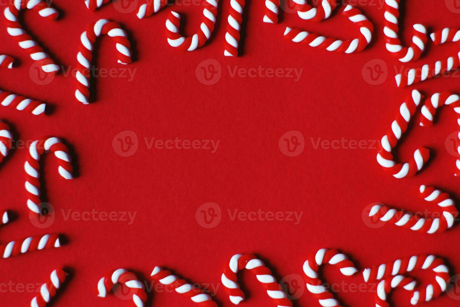 Flat lay Christmas composition with frame of candy canes on a red background. Copy space for text photo