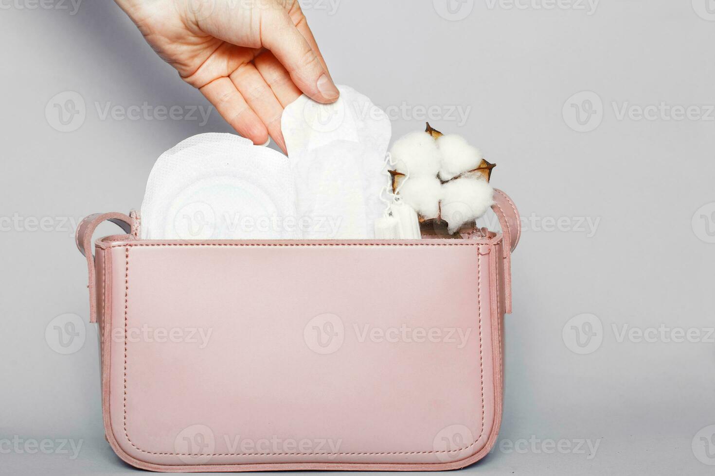 mano de mujer saca panty liner de bolsa de cosméticos rosa con tampones y toallas sanitarias femeninas foto