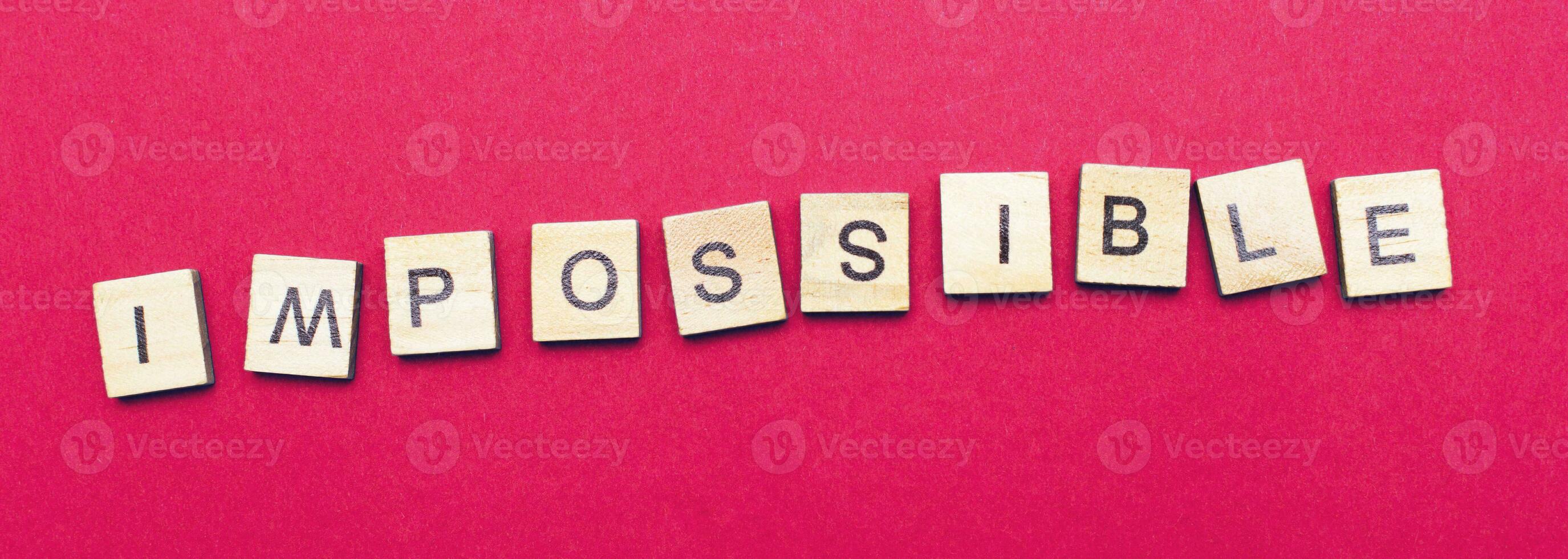 Impossible word made by wooden cubes isolated on pink paper background. Business problem comcept photo