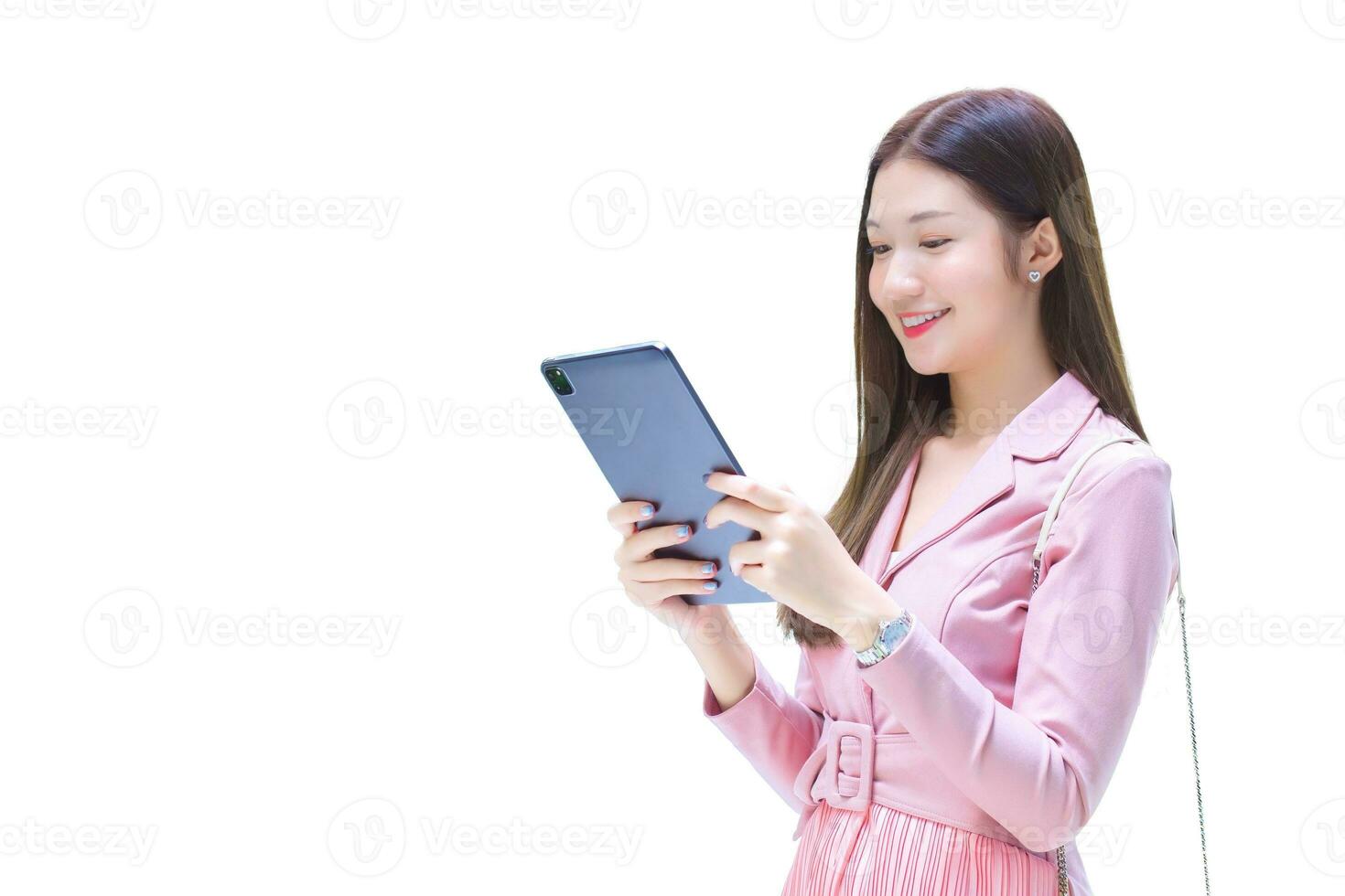 Beautiful young Asian professional business woman with long hair is smiling outdoor in the office while hold at the tablet in her hand to go out meeting while isolated on white background. photo