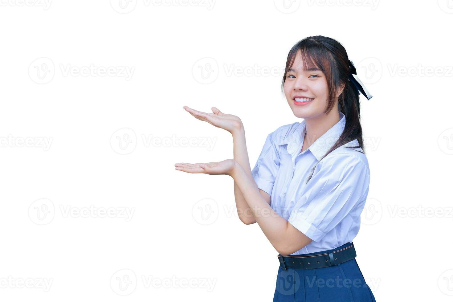 Cute young Asian high school student girl in school uniform with smiles confidently while she looks at camera to present something happily while studying isolated on white photo