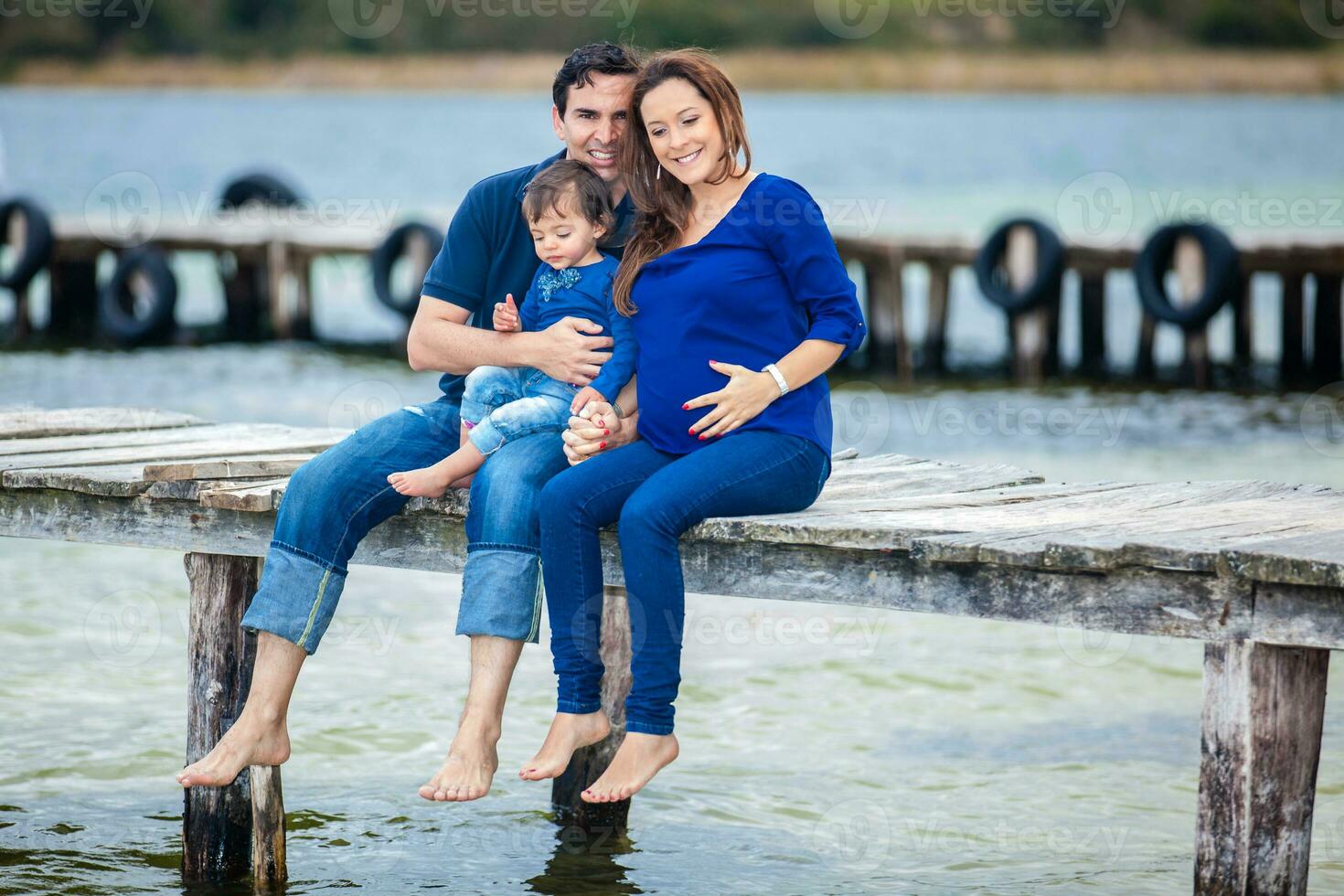 Young couple waiting for their second baby having fun with their baby girl at the beautiful white beach of Lake Tota located in the department of Boyaca at 3,015 meters above sea level in Colombia photo