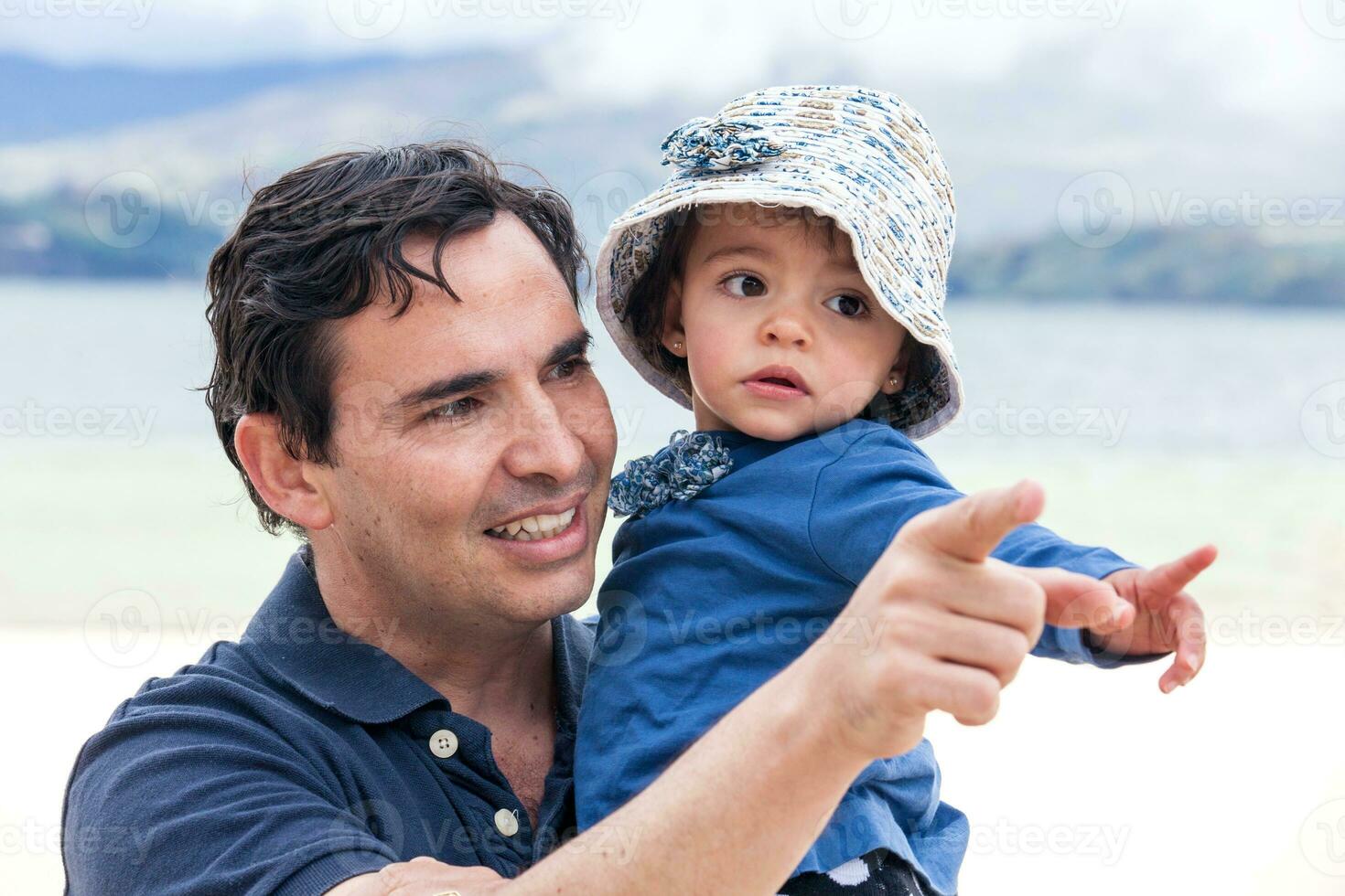 Young father having fun with his baby girl at the beautiful white beach of Lake Tota located in the department of Boyaca at 3,015 meters above sea level in Colombia photo