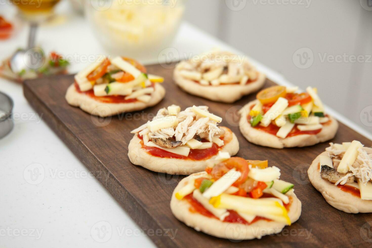 Ready to be baked mini pizzas. Delicious home made mini pizzas preparation. photo