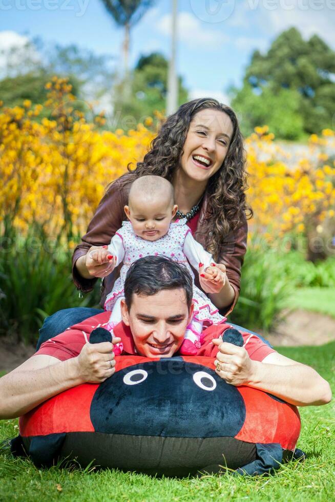 joven padres teniendo divertido al aire libre con su seis meses antiguo bebé muchacha. felicidad concepto. familia concepto foto